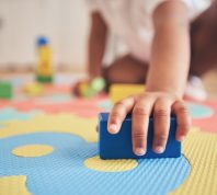 closeup of a toddler holding a block on a play mat
