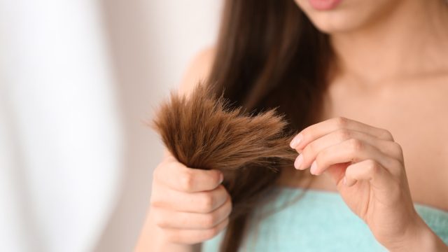 Woman with damaged hair on blurred background, closeup