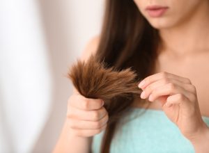 Woman with damaged hair on blurred background, closeup