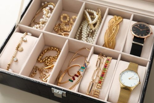 Elegant jewelry box with beautiful bijouterie and expensive wristwatches on table, closeup