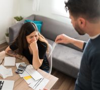 Sad young woman crying with her husband while doing their taxes because of their financial and money problems