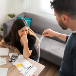 Sad young woman crying with her husband while doing their taxes because of their financial and money problems