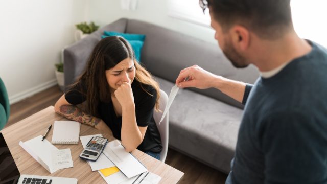 Sad young woman crying with her husband while doing their taxes because of their financial and money problems