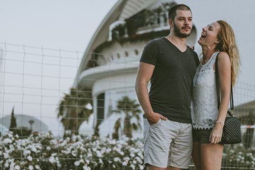 Young handsome couple enjoying in the park - the girl is teasing her boyfriend. Travelers in Valencia, Spain
