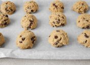 chocolate chip cookie dough balls on a baking sheet with parchment paper