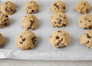 chocolate chip cookie dough balls on a baking sheet with parchment paper