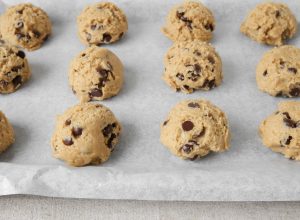chocolate chip cookie dough balls on a baking sheet with parchment paper