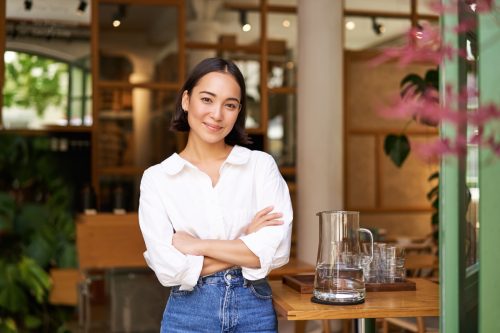 Portrait of smiling girl in white collar shirt, working in cafe, managing restaurant, looking confident and stylish.