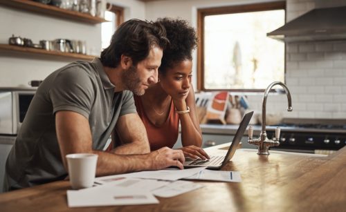 couple looking at a laptop while sitting at their kitchen counter