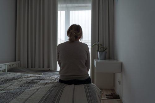 Mature woman sitting alone in the room, sad depressed person. Back view. mental health
