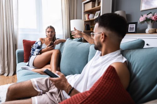 Young married couple husband and wife sitting at home having problems in their marriage and a cold relationship. A boyfriend and a girlfriend have an argument about spending too much money.