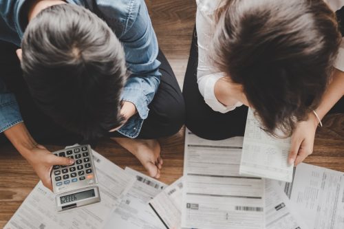 Top view couple sitting on the floor stressed and confused by calculate expense from invoice or bill,have no money to pay think of taking the house to mortgage causing debt,bankruptcy concept.