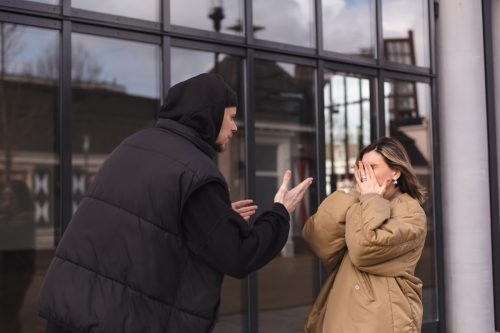 Young arguing sad couple two friends family man woman in casual clothes screaming scolding together walking outdoor. Man yelling at woman, she cover face. Couple arguing, having relationship problem
