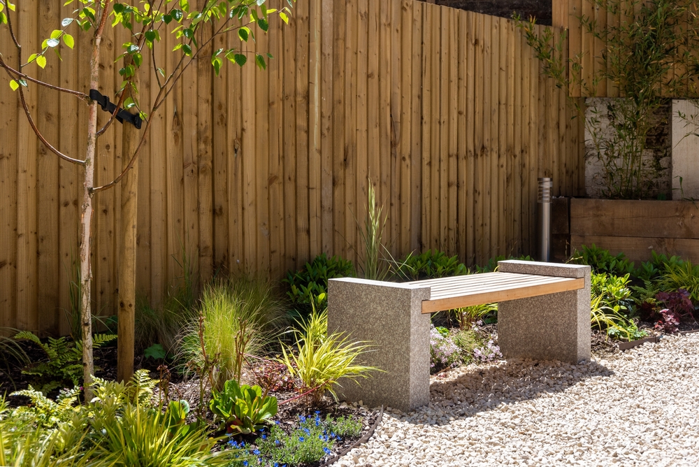 A bench next to a fence in a garden