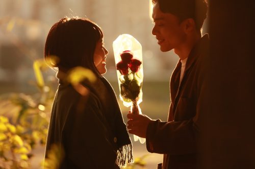 Man handing bouquet of roses to a woman