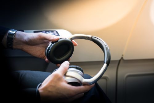 A passenger is holding noise-cancelling headphones of a business class cabin.