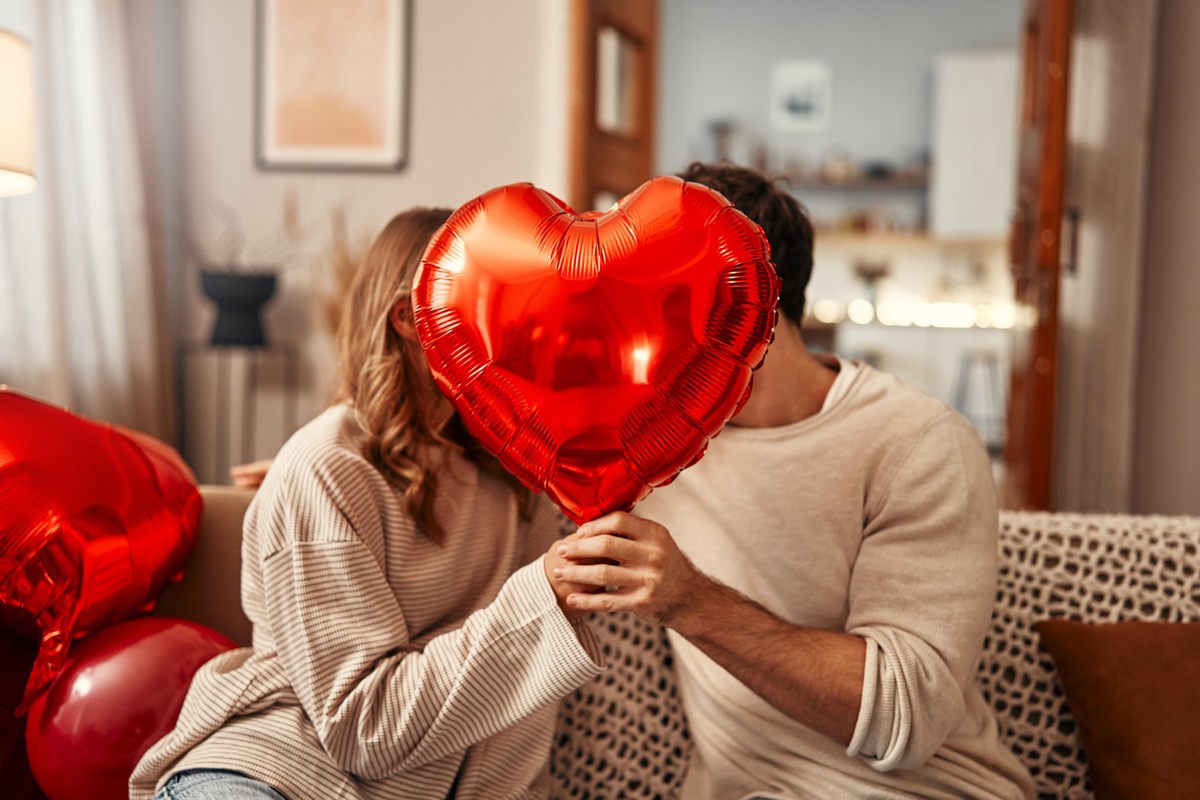 Man and woman kissing behind red hard balloon