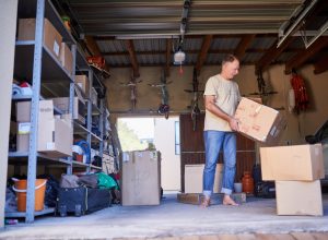 Clearing out some things. Shot of a man carrying a box in a garage.