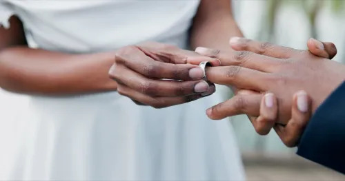Close up of bride placing silver wedding ring on man's finger