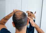 Man looking at bald spot in mirror
