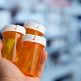 Hand holding many empty orange bottles of medicine in a hospital