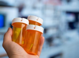Hand holding many empty orange bottles of medicine in a hospital