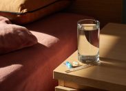 medicine, a thermometer and a glass of water on the bedside table in the morning
