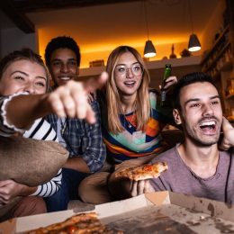 people watching a TV screen with pizza
