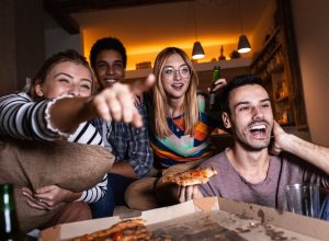 people watching a TV screen with pizza
