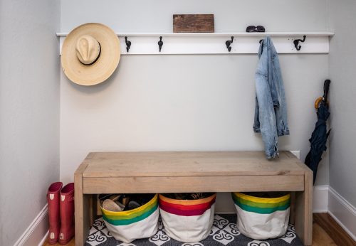 A small entrance mudroom with hooks for hanging jackets and hats, as well as a bench