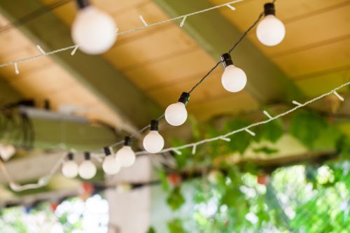 Closeup of outdoor string lights hanging from a covered porch