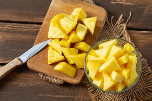 pineapple chunks on a cutting board with a knife