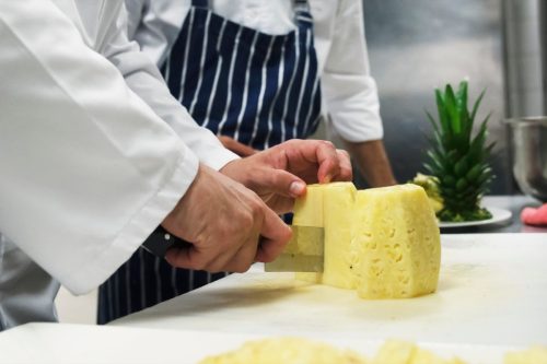 chef cutting pineapple halves into fourths