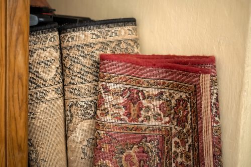 Old unused decorative carpets stored away, home carpet storage, garage sale items, used second hand household goods abstract concept, getting rid of, nobody, object closeup, no people. Two carpets