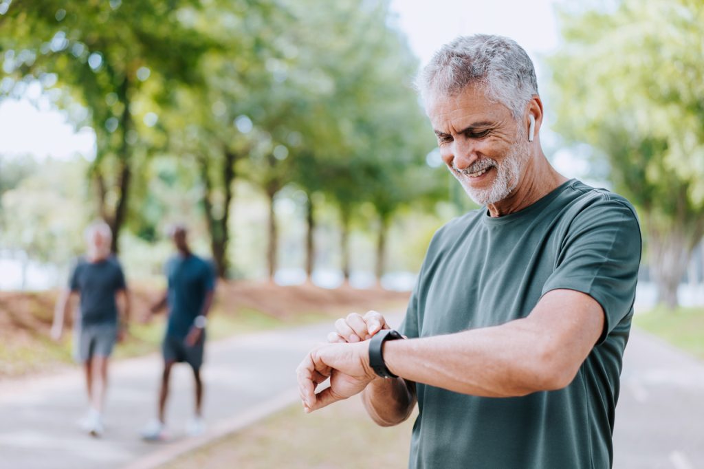 A senior man looking at his smartwatch and smiling during a run
