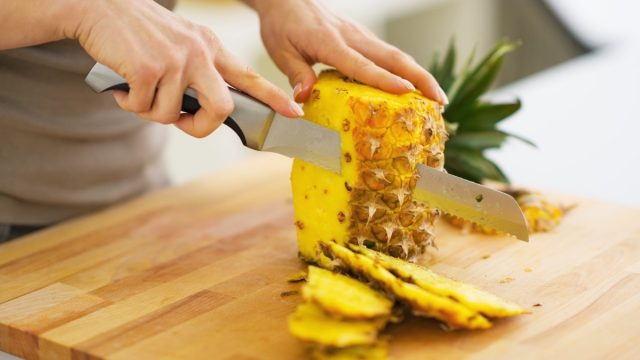 woman cutting pineapple