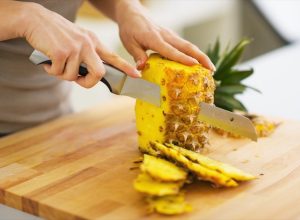 woman cutting pineapple