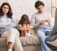 Unhappy child with parents in family therapy
