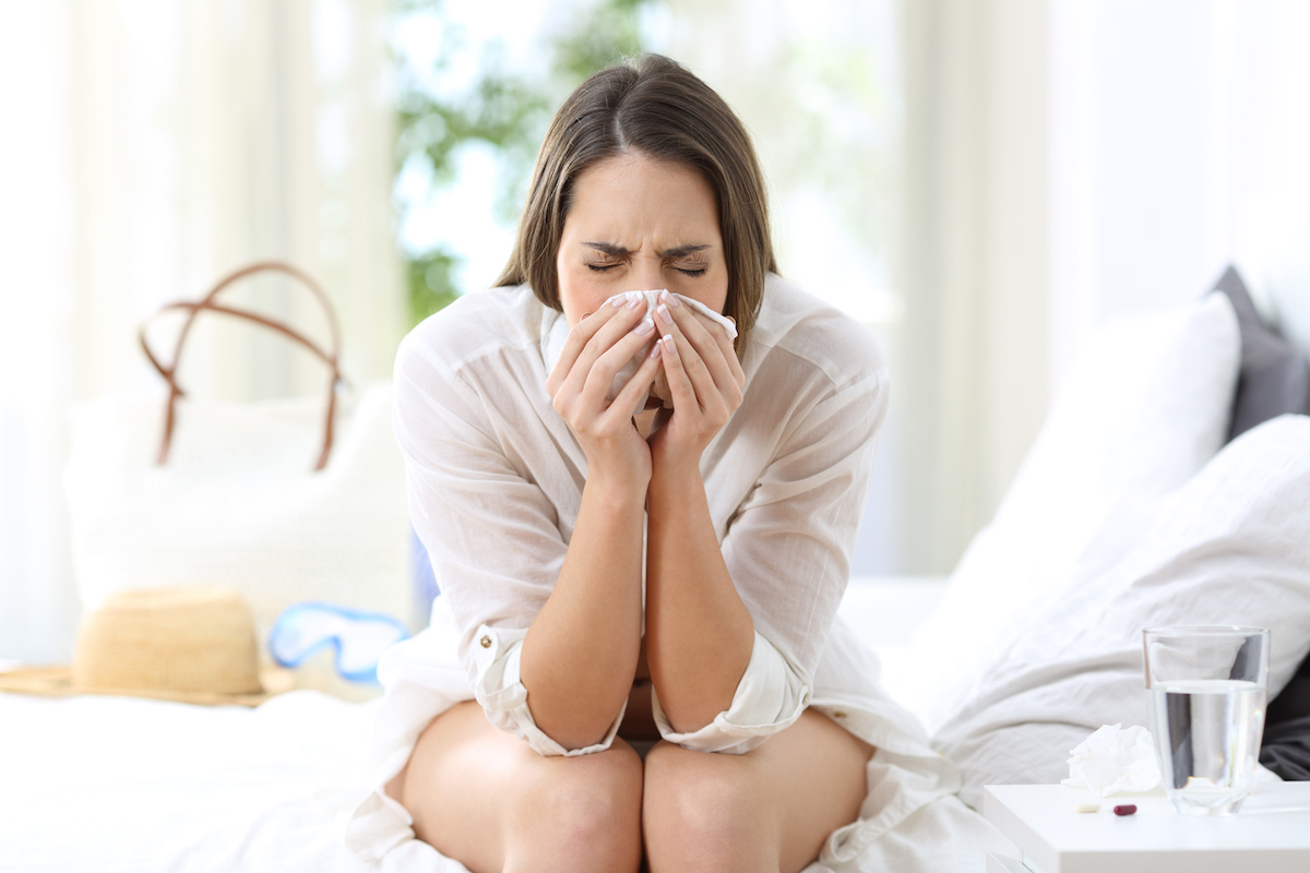 sick woman coughing in a hotel room while on a summer vacation