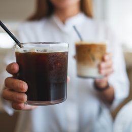 Closeup of a woman holding and serving two glasses of iced coffee