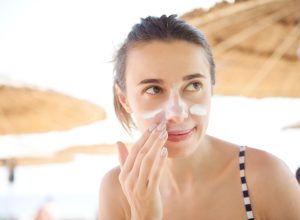 beautiful woman smears face sunscreen at the beach for protection.