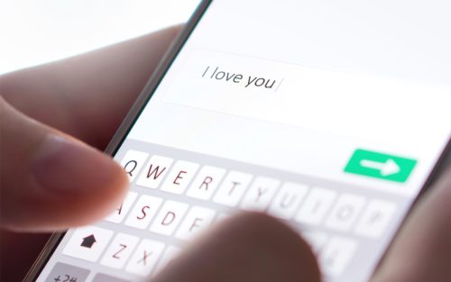 Close up on person typing "i love you" text into smartphone