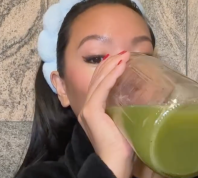 still from a video of a young woman drinking celery juice
