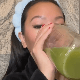 still from a video of a young woman drinking celery juice