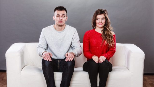 man and woman in a situationship sit awkward on a couch