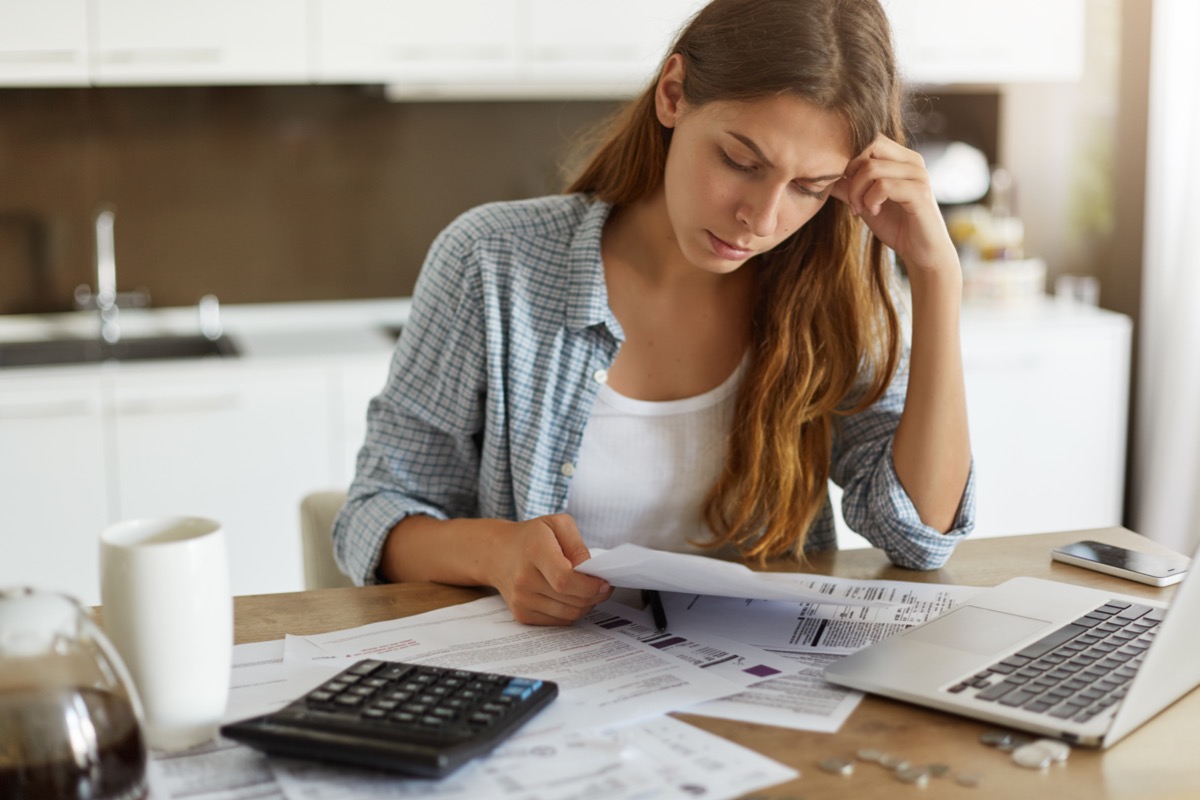woman looking at bills with her computer and a calculator in front of her