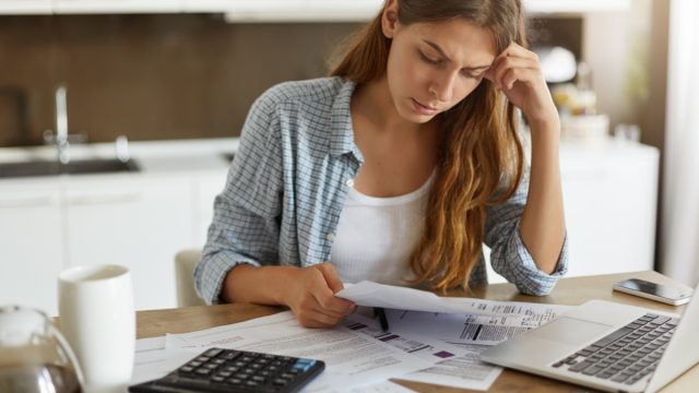 woman looking at bills with her computer and a calculator in front of her