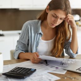 woman looking at bills with her computer and a calculator in front of her