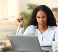 woman looking suspiciously at her laptop scream