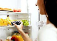 woman reaching for fruit in the fridge
